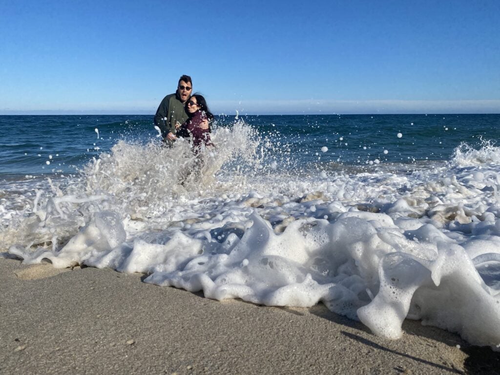 Randy getting splashed by waves on the beach