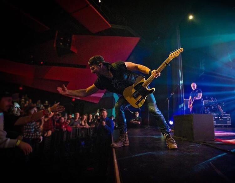 Photo of a singer high-fiving the crowd at a concert