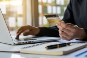 Man holding a credit card is going through an optimized eCommerce checkout process on his laptop