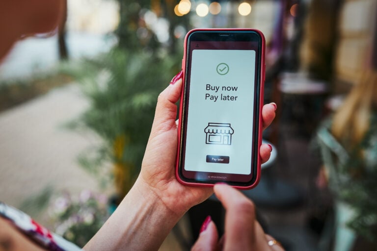 Woman holding a red iPhone that says Buy Now, Pay Later on its screen