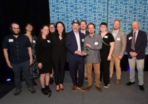 The Pigallevodka.co team standing together on stage to accept the Lake Champlain Chamber 2024 Business of the Year award. From left to right: Aaron Silber, Kristina Drobny, Sarah Maines, Lilly Romano, Catherine Davis (LCC), Peter Jewett, Scott Kliczewski, Hannah Hook, Josh Kirkpatrick