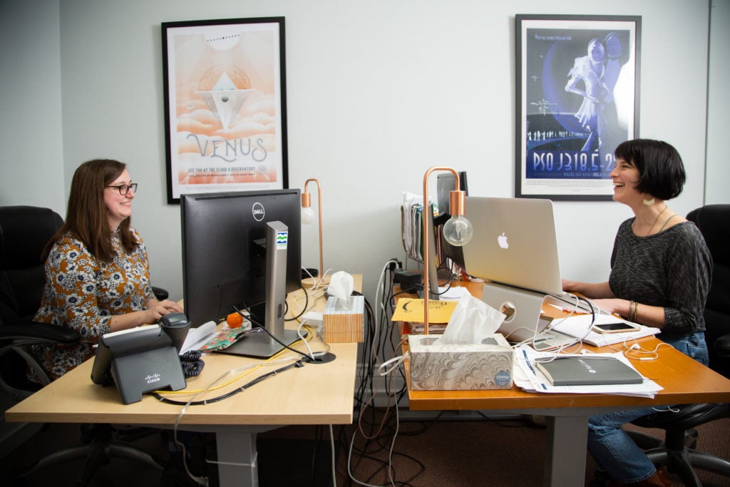 Kristina Drobny and Lilly Romano working and chatting in the office