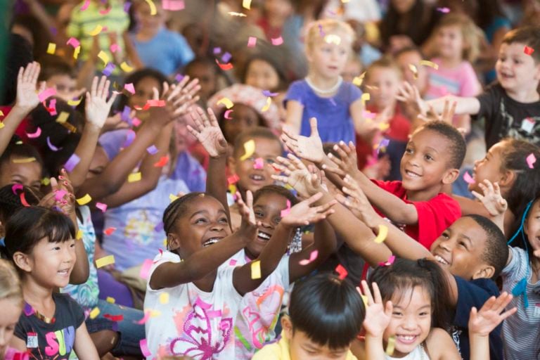 Children reaching out to grab falling confetti