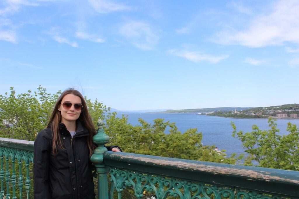 Photo of Shea in front of a scenic lake overlook