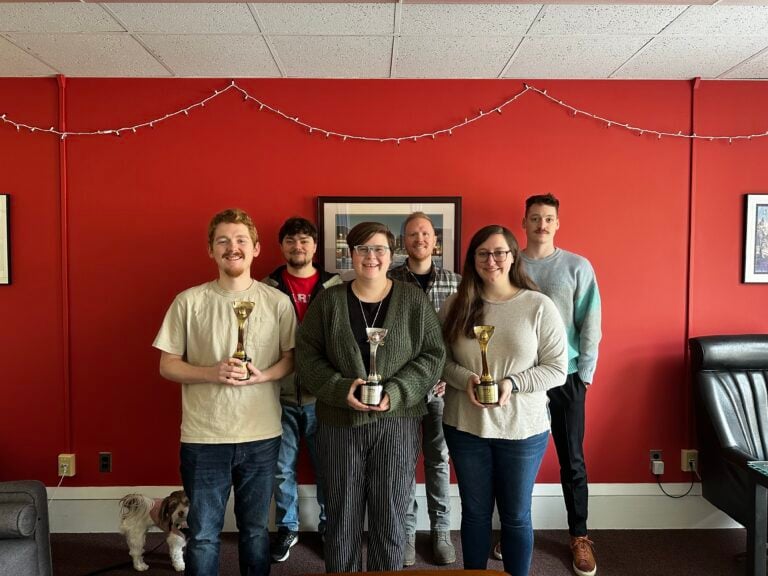 6 people smiling in a room, some holding trophies