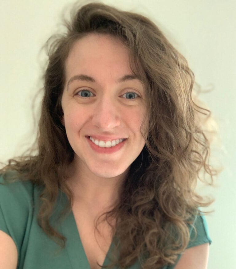 Smiling woman with curly brown hair and a green shirt