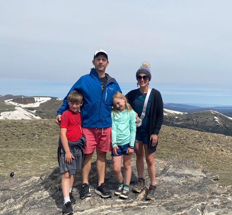 Kristina and her family stand at the top of a peak in The Rocky Mountain National Forest during their vacation in Summer 2022