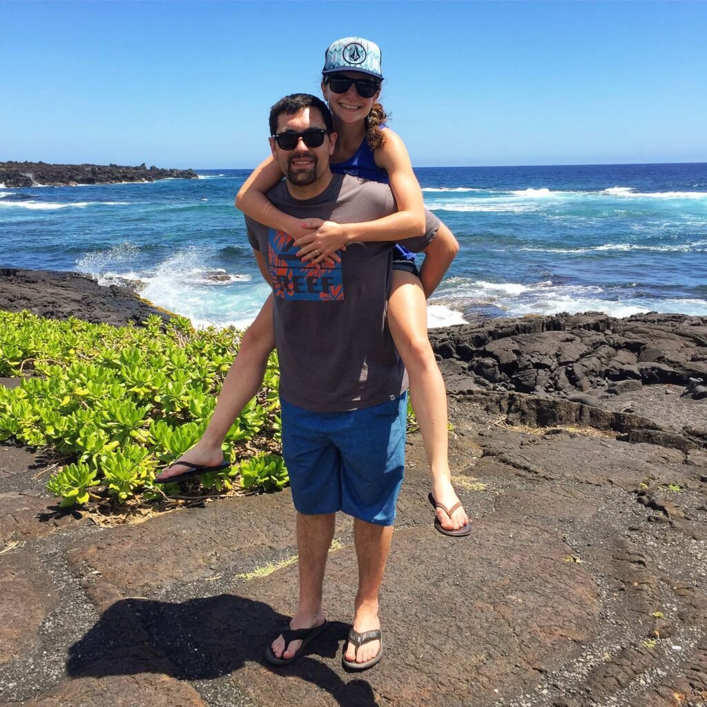 Sarah and her husband in front of an ocean coastline