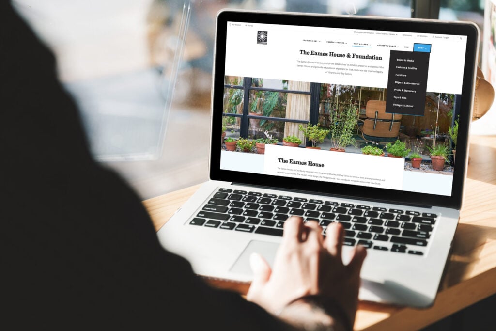 Person scrolling on a laptop looking at the Eames Office website