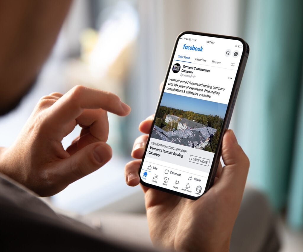 Man holding an iPhone with a Vermont Construction Company Facebook Ad on its screen