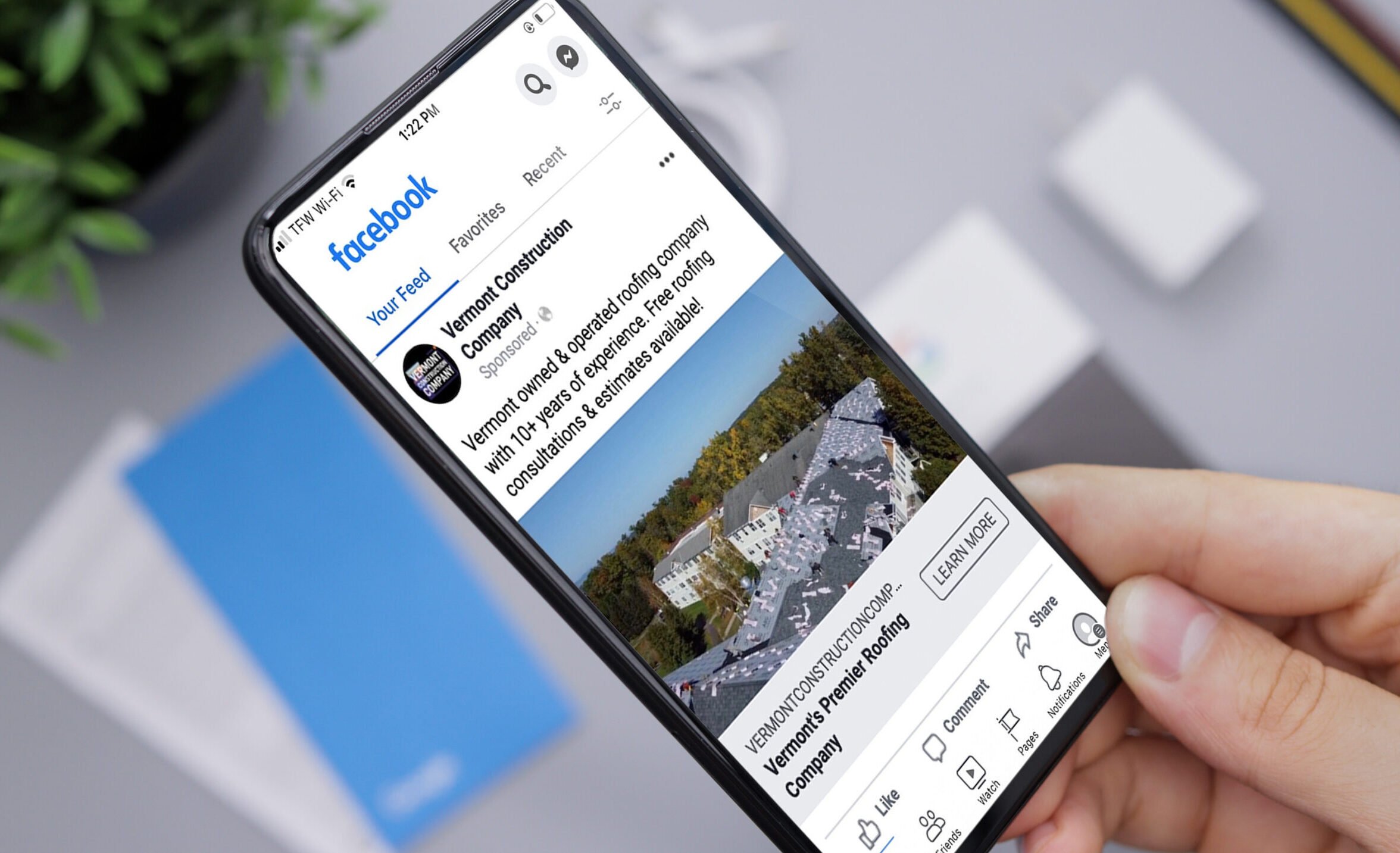 Person holding an iPhone with a Vermont Construction Company Facebook ad on its screen