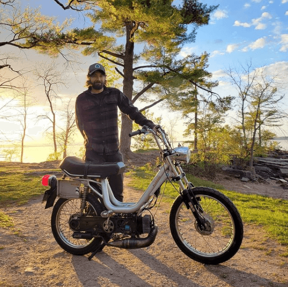 Colin Urban standing behind a moped