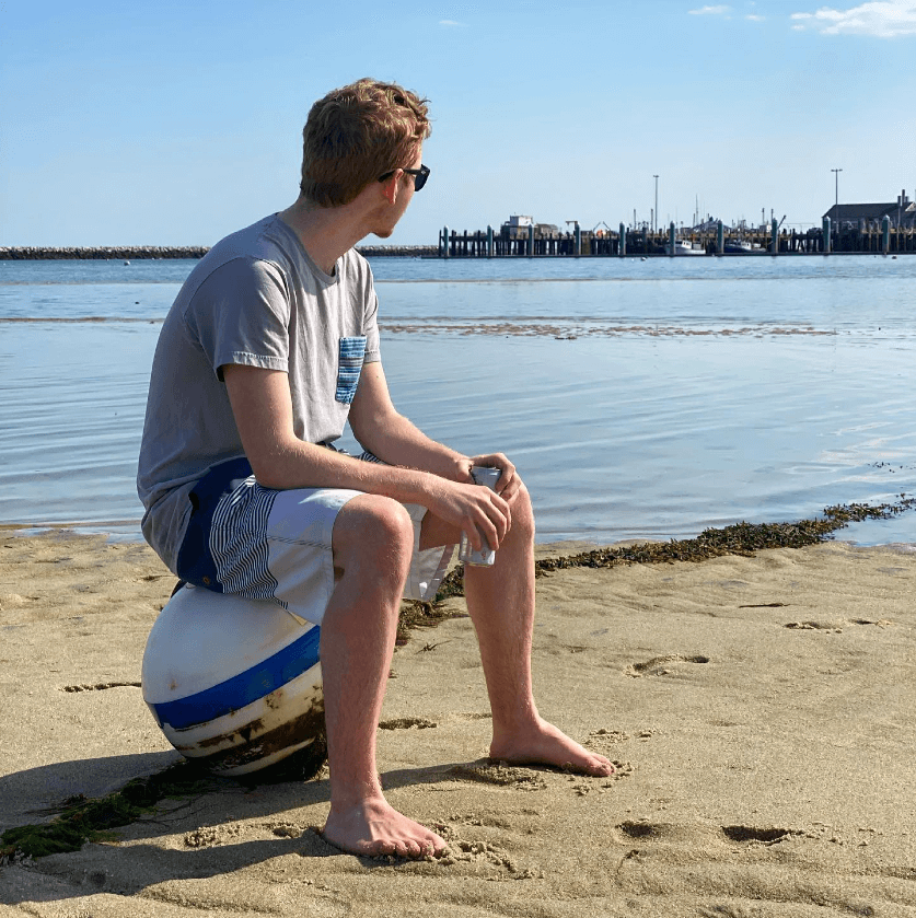 Scott sitting on a beach ball by the water